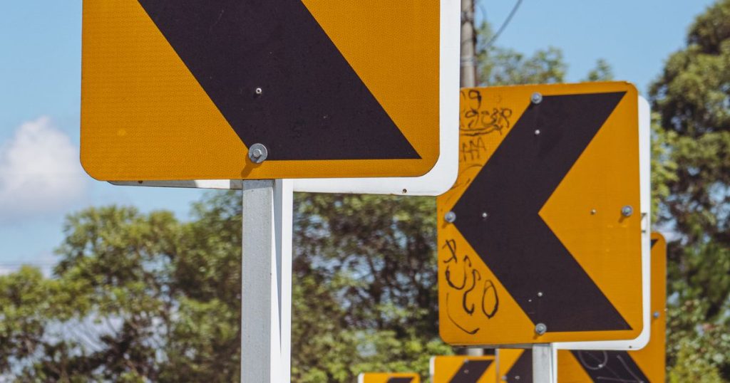 Yellow and black chevron curve warning signs beside a road
