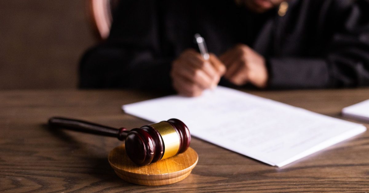 Judge signing papers beside a gavel