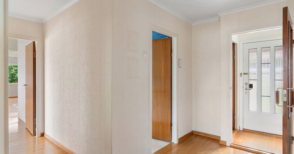 A home hallway with wooden floors and open doors leading to other rooms.