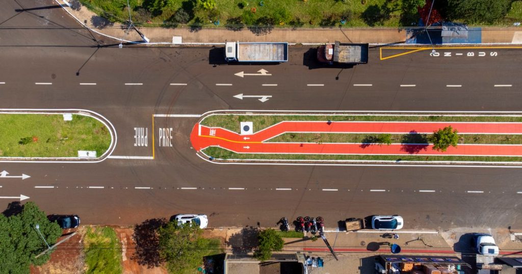 Aerial view of a city street with a red bike lane and parked trucks