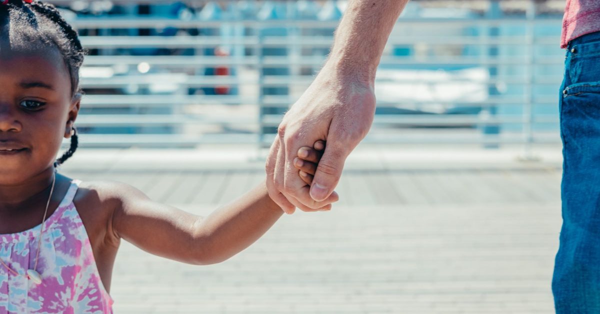 Parent holding a young child by the hand
